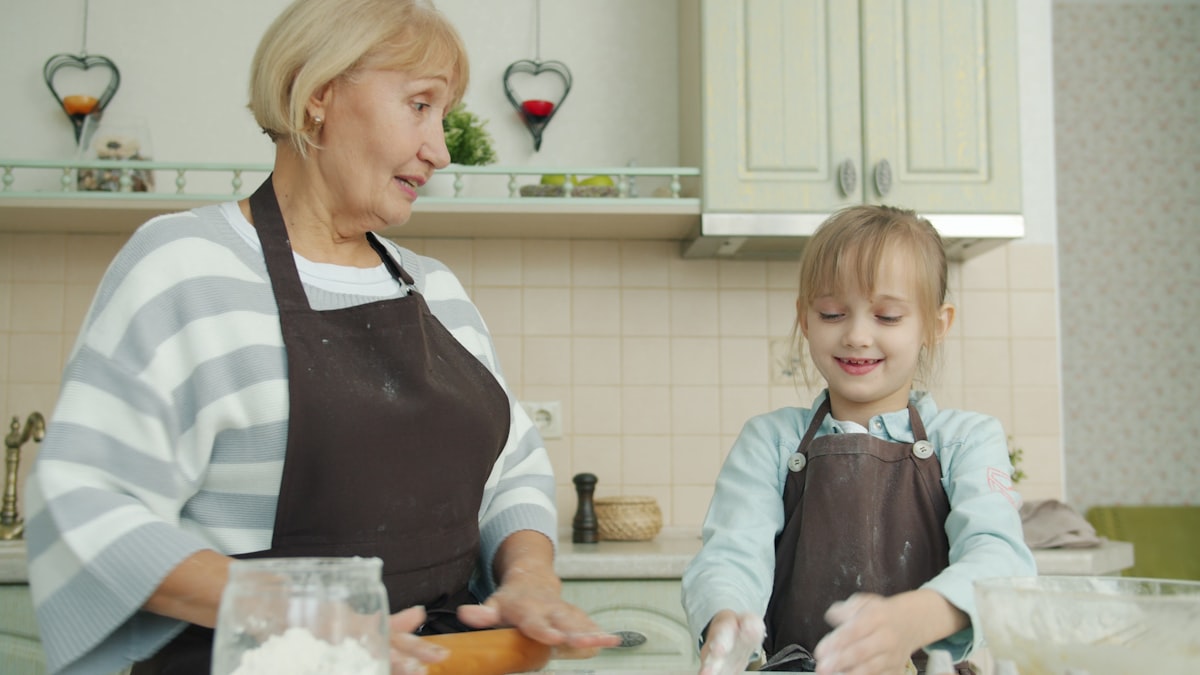 Parent and child smiling while preparing fresh vegetables during an online cooking class